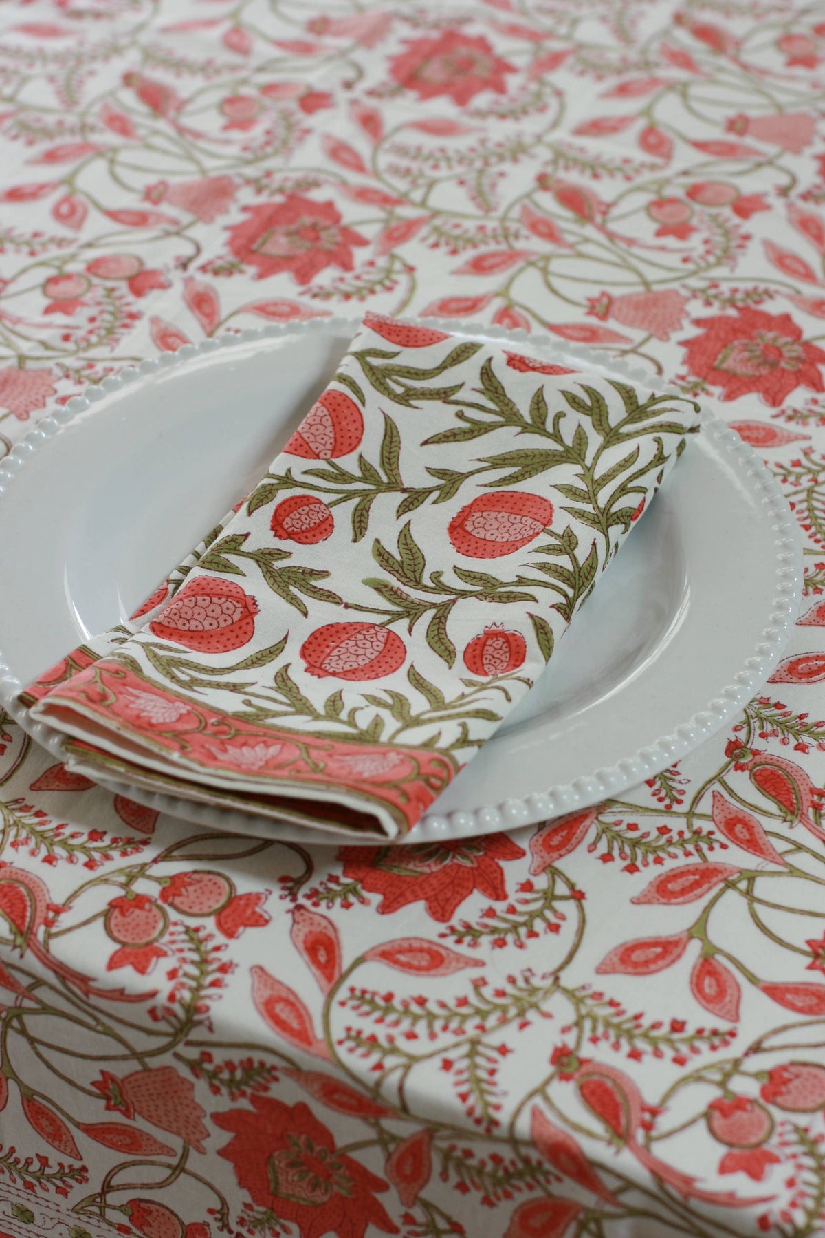 Floral tablecloth with a plate and folded napkin on a matching pattern.