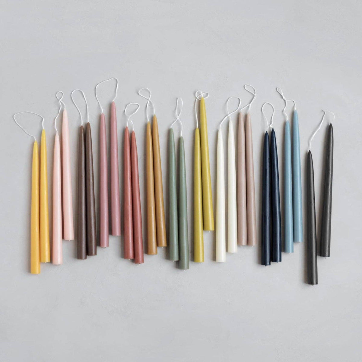 Set of colorful candles hanging against a light gray background