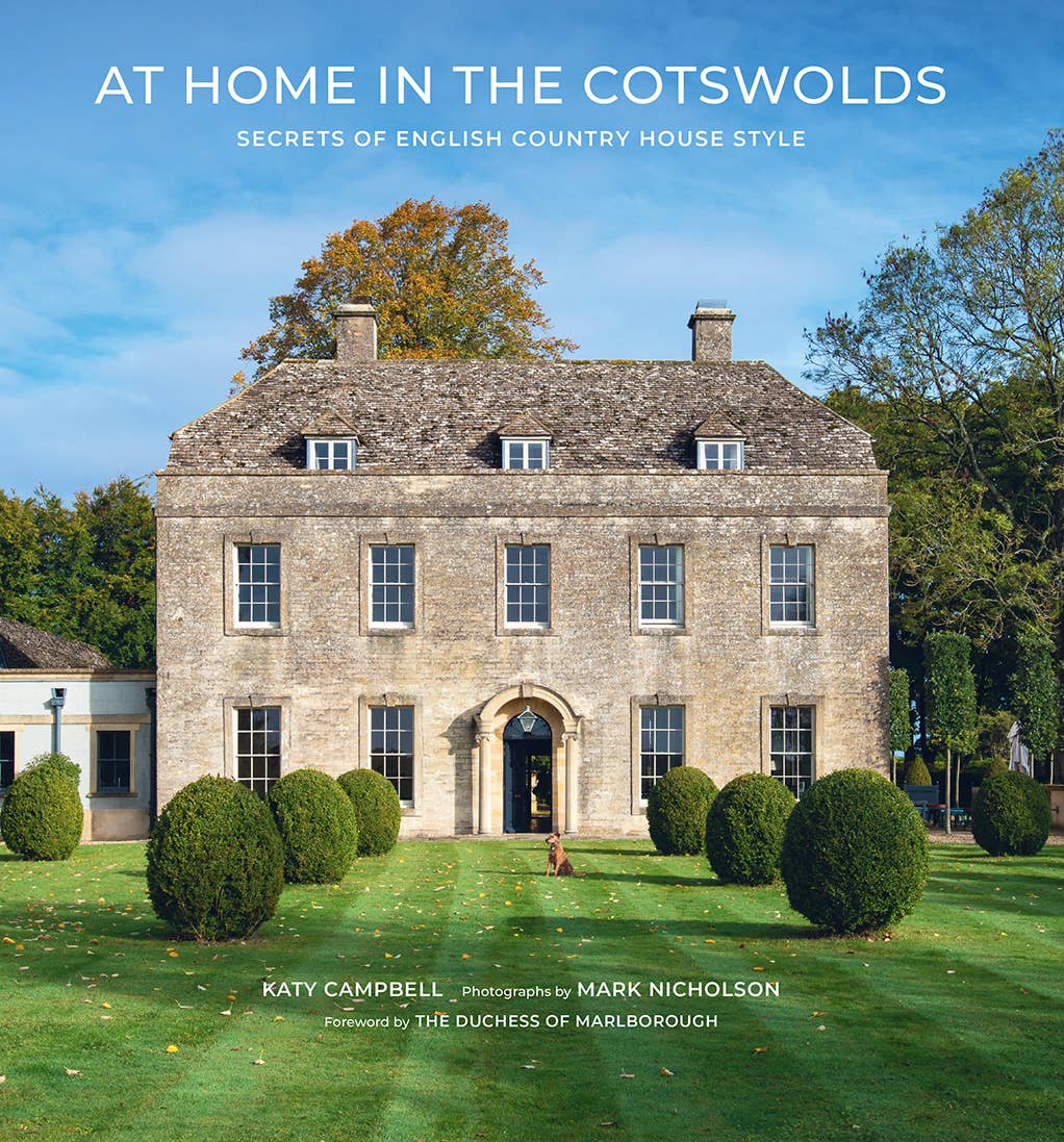 Book cover of 'At Home in the Cotswolds' with a large stone house and garden.