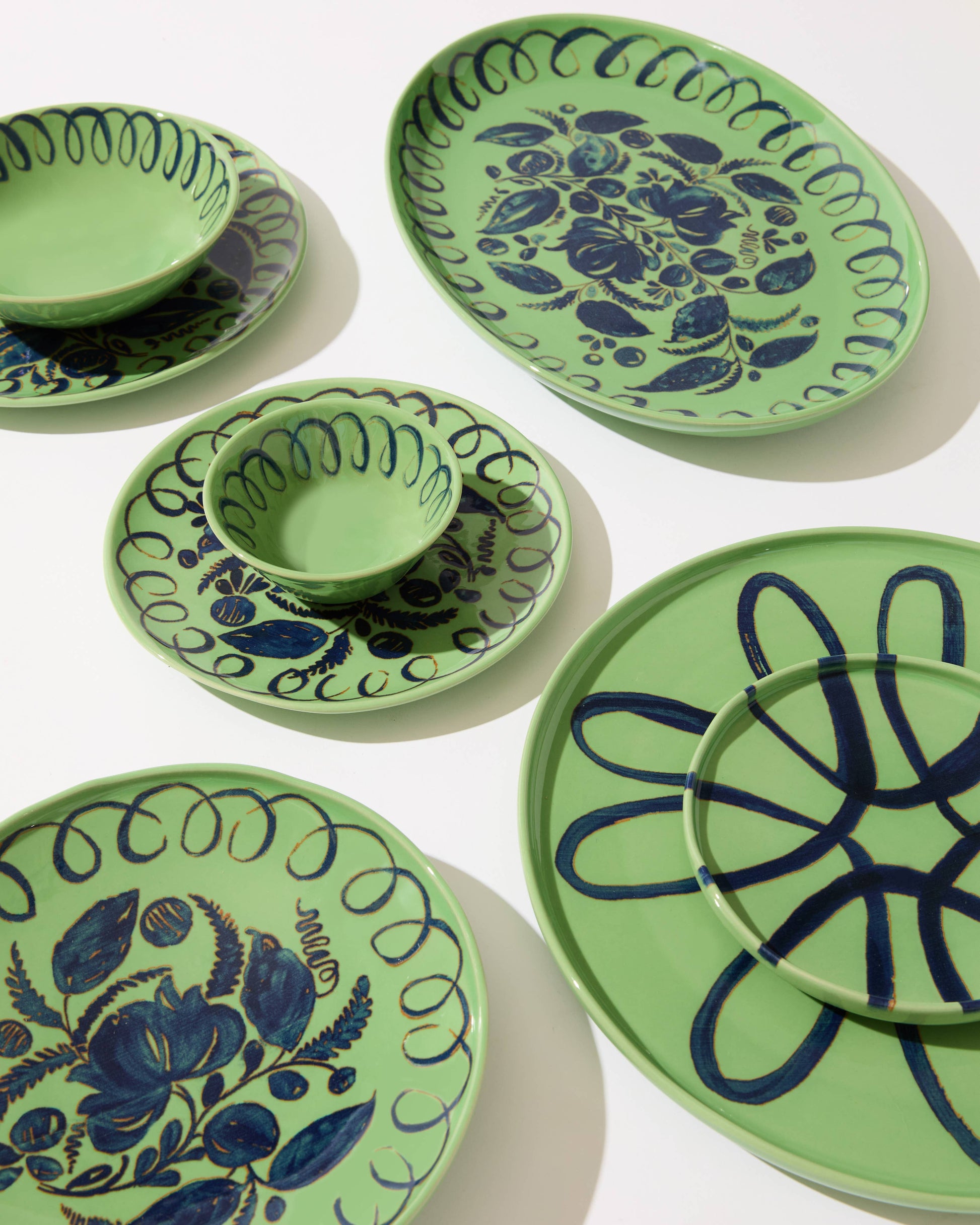 Green ceramic plates with blue floral patterns on a white background