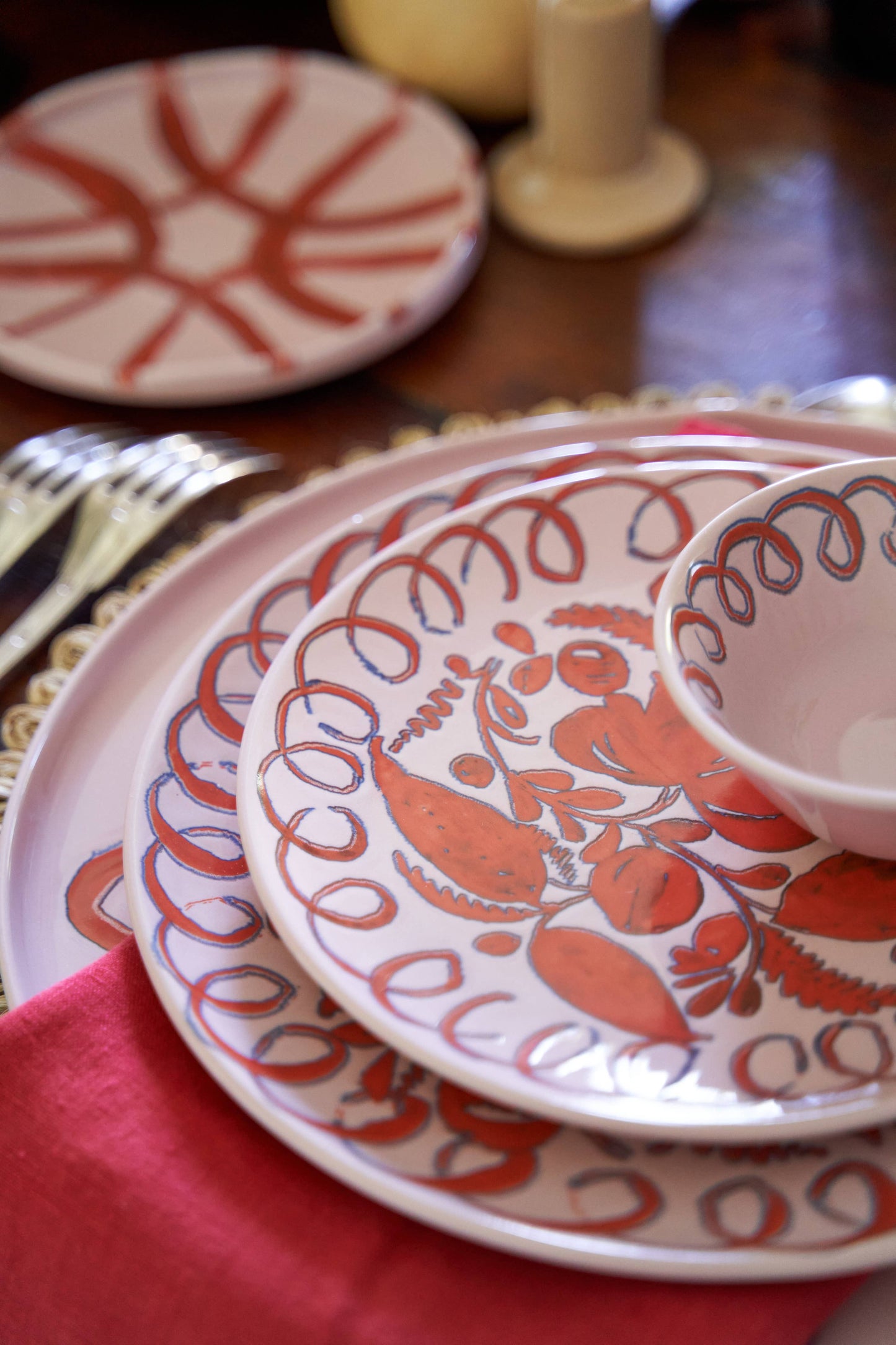 Stack of patterned ceramic plates on a table with a red cloth.