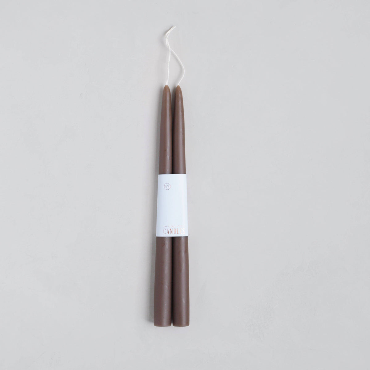 Two brown candles with a white label on a light gray background
