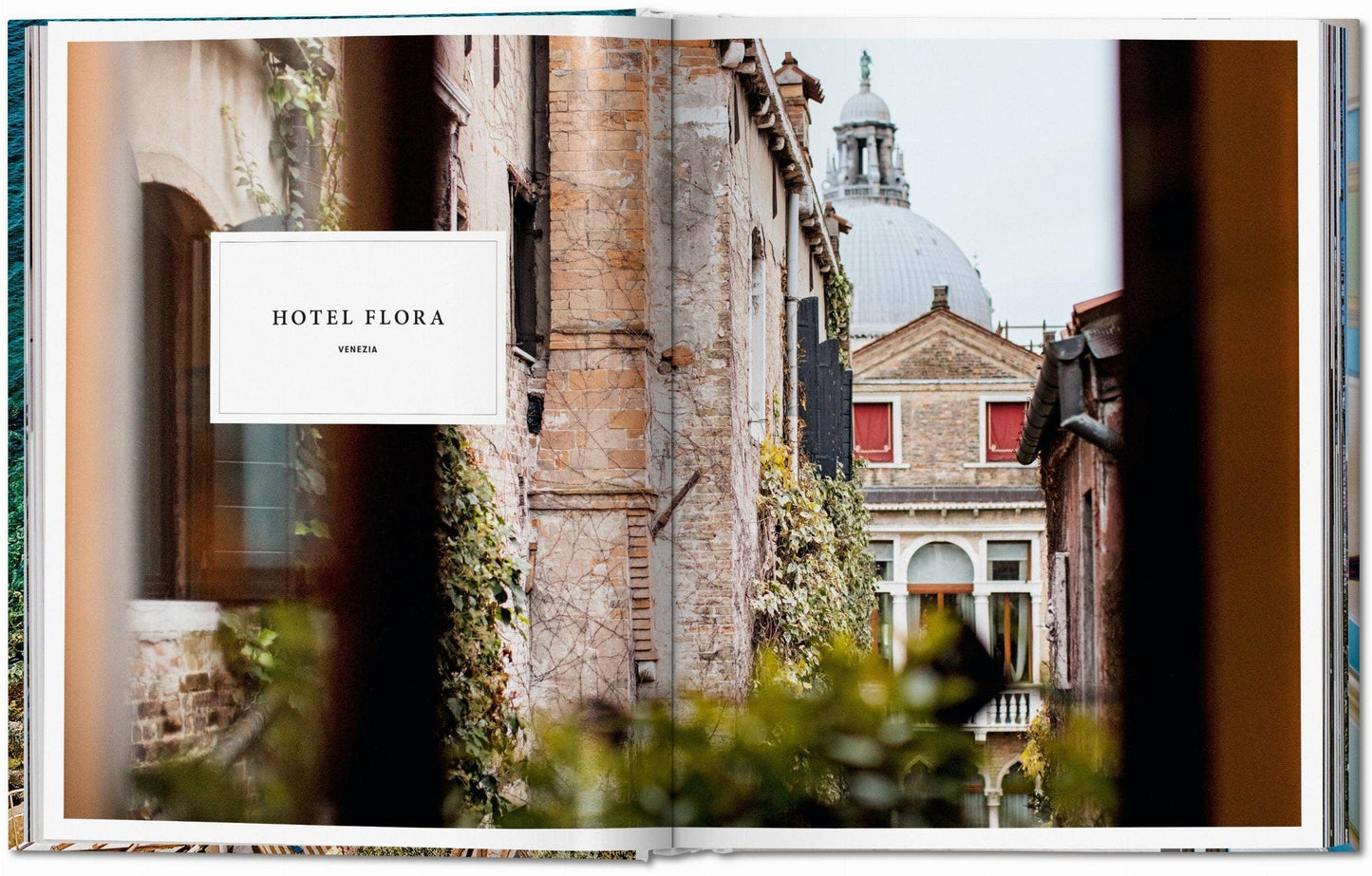 Open book showing a photograph of Hotel Flora with a scenic background Le Marchande
