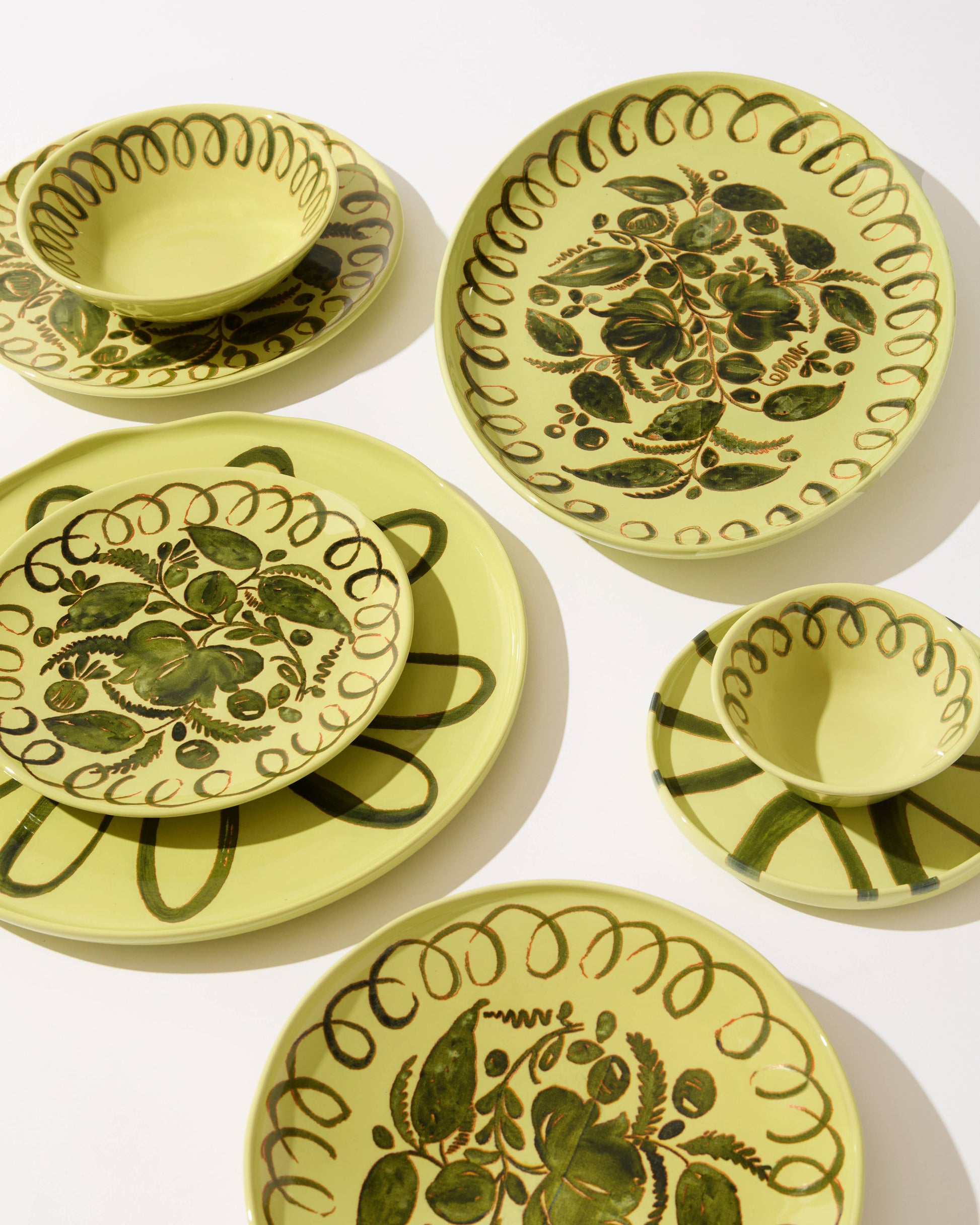 Set of green ceramic plates with floral patterns on a white background
