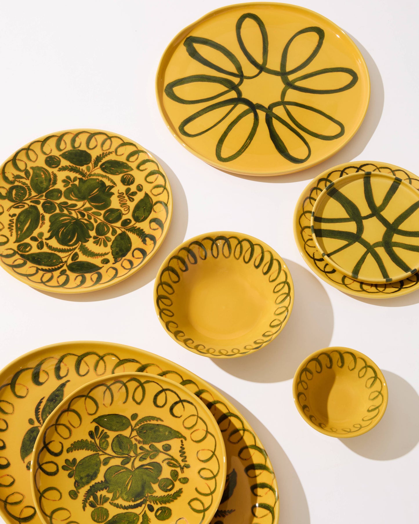 Set of yellow ceramic plates with green floral patterns on a white background