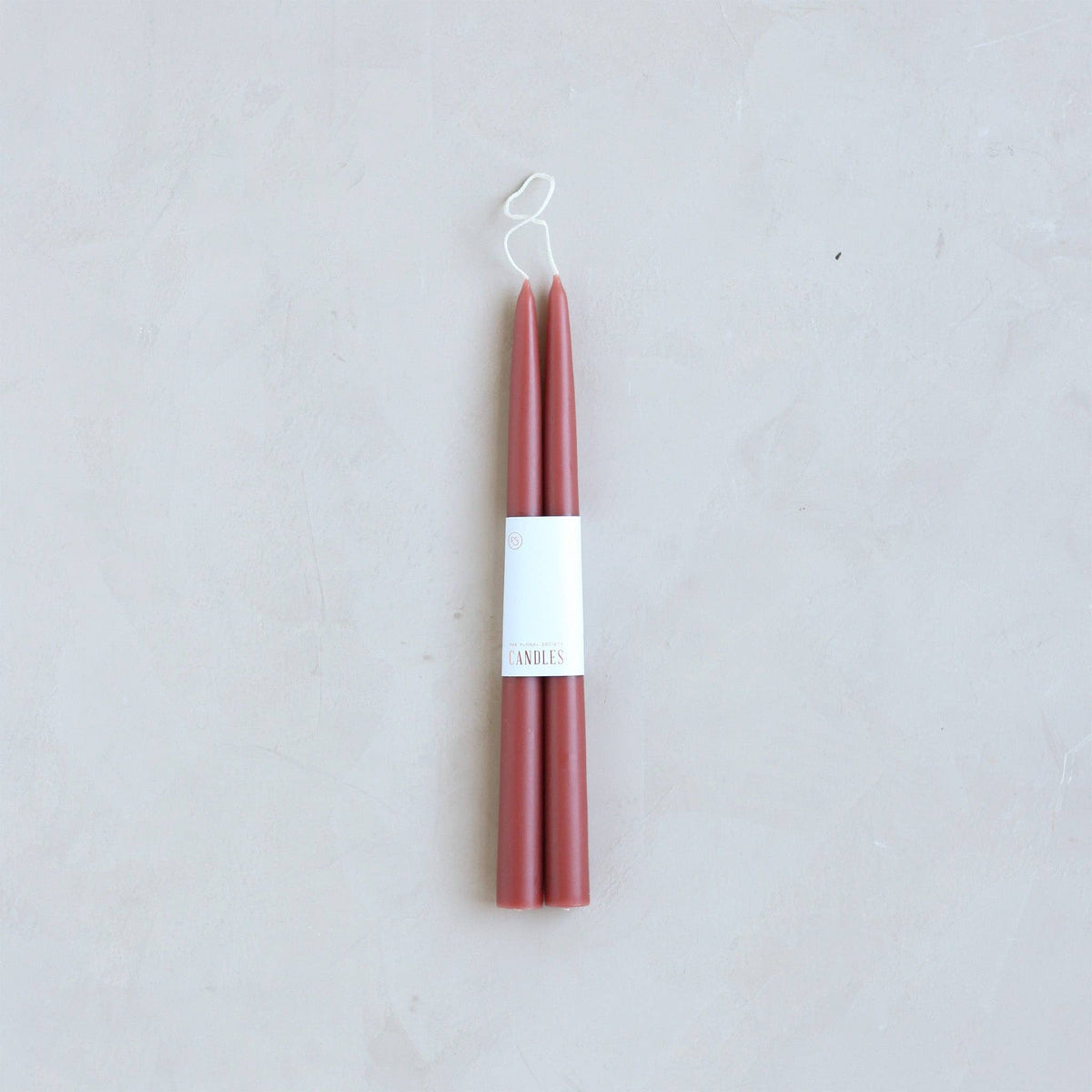 Pair of red candles on a white background with a visible brand label.