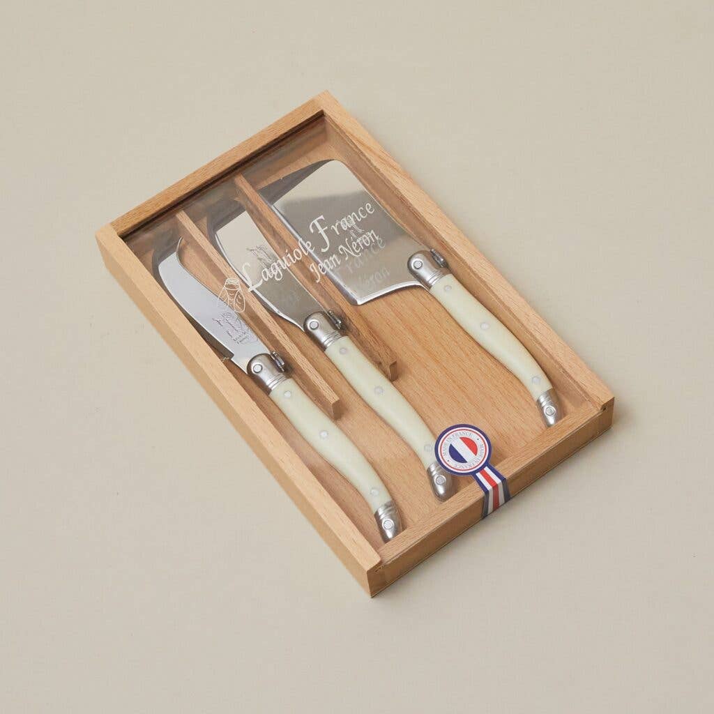 Set of four cheese knives with wooden handles in a box on a beige background