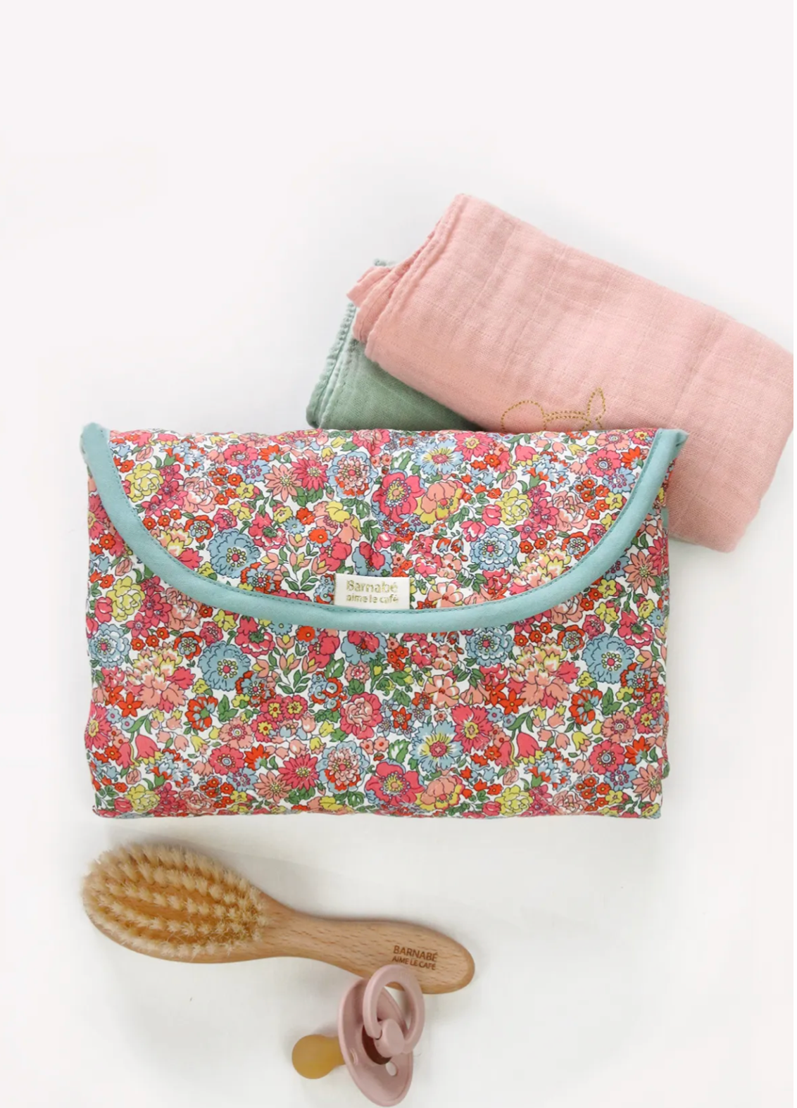 Floral-patterned baby changing bag with a pink blanket, brush